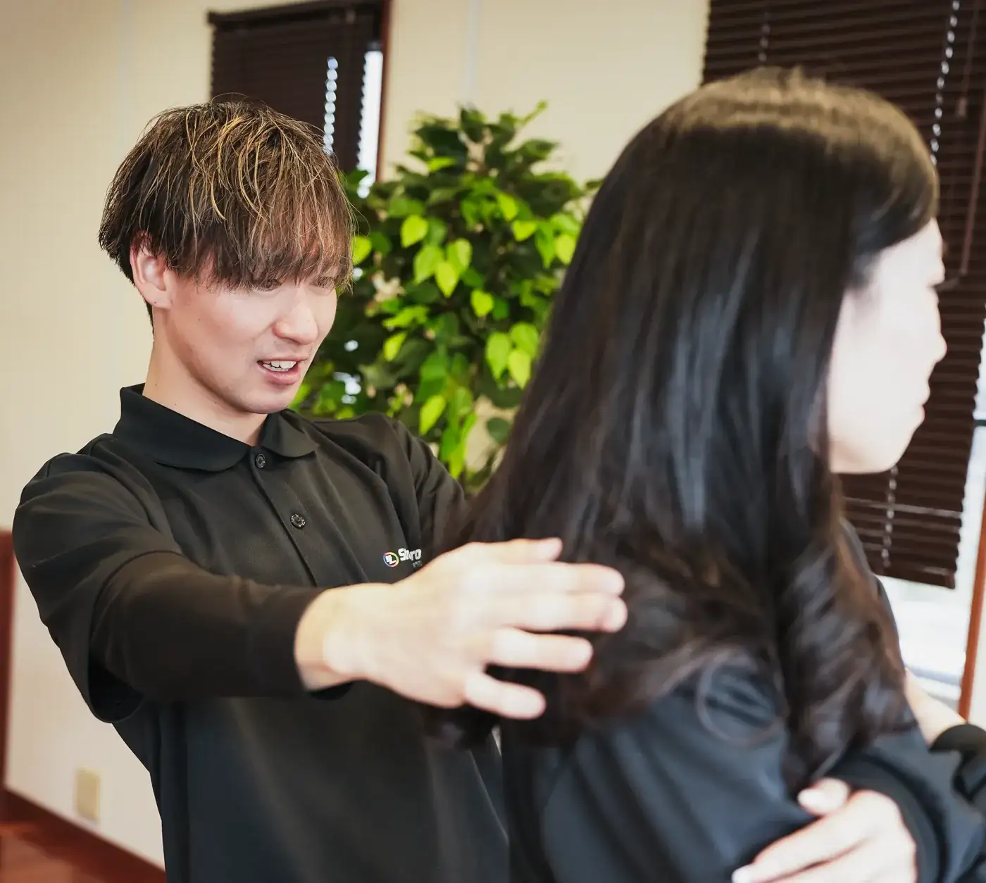 相手の肩に手を添え、身体の状態を確認するトレーナー